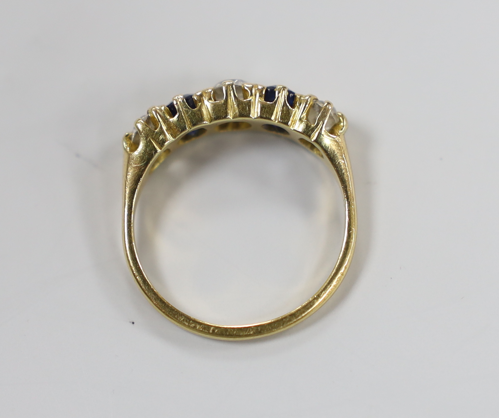 An 18ct, three stone diamond and two stone sapphire set half hoop ring, size M, gross weight 3.3 grams.